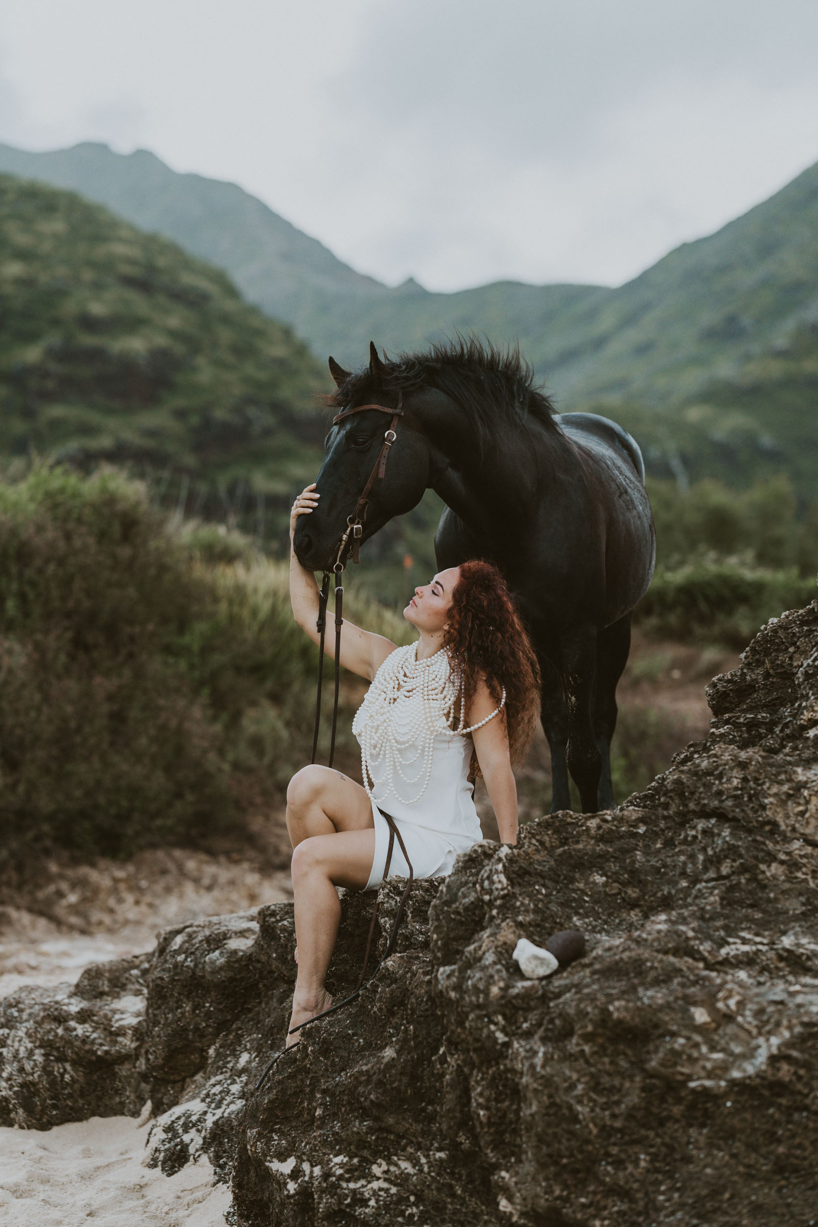 a girl sitting on a rock and her horse