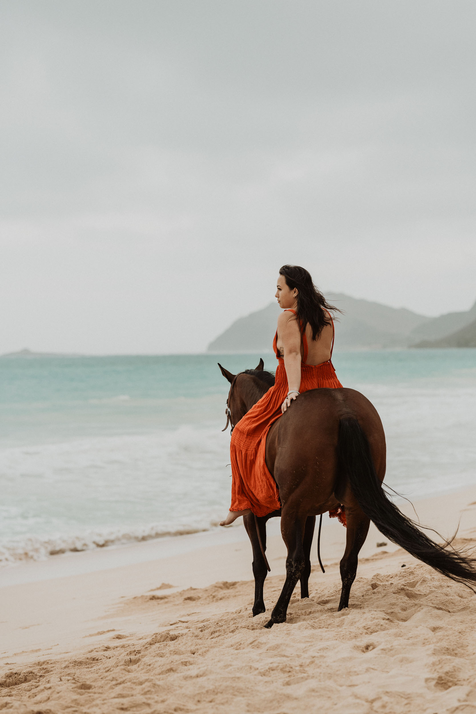 a girl riding her horse on a beach in hawaii
